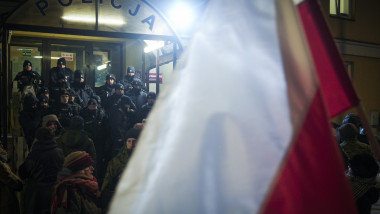 Steag polonez fluturat dintr-o mulțime aflată în fața unei secții de poliție
