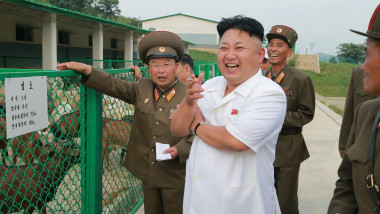 Kim Jong Un cu o țigară în mână râde alături de niște militari lângă un gard