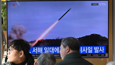 People watch a television screen showing a news broadcast with file footage of a North Korean missile test