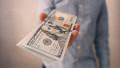 un bărbat înmânează un teanc de bancnote de dolari