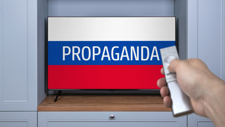 televizor pe care apare mesajul „Propaganda” pe fundalul steagului Rusiei