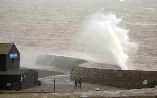 Dog walkers get a soaking on the Cobb Wall in Lyme Regis, Dorset as Storm Isha approaches.