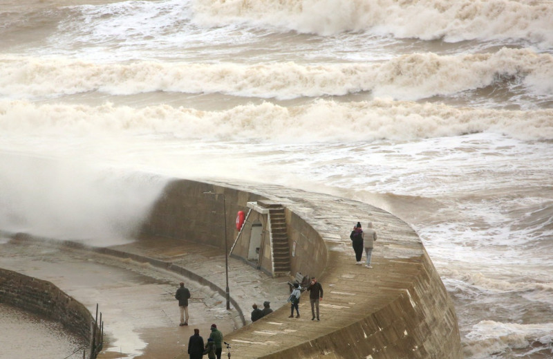 Dog walkers get a soaking on the Cobb Wall in Lyme Regis, Dorset as Storm Isha approaches.