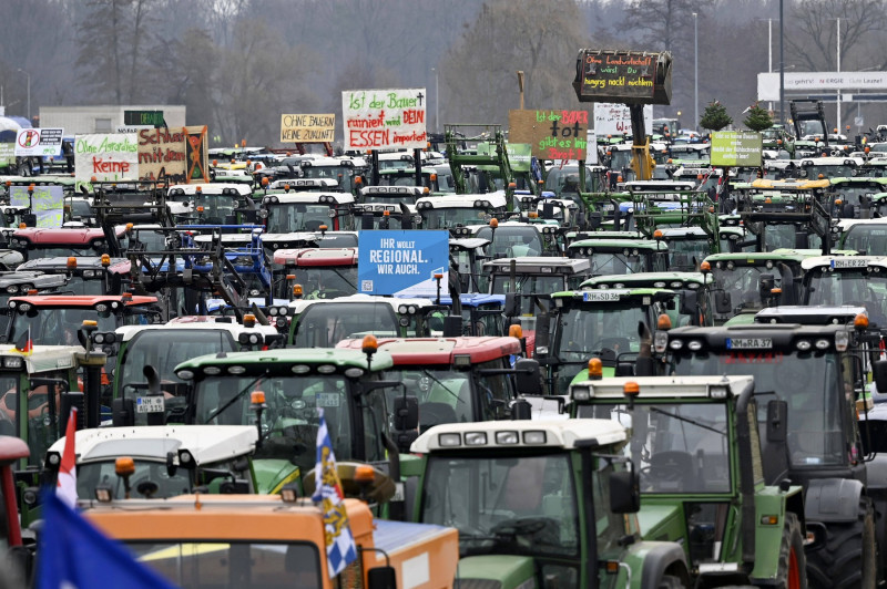 Teilnehmer der Bauernproteste fahren in Nürnberg mit ihren Traktoren im Korso und präsentieren dabei Schilder mit Aufsch