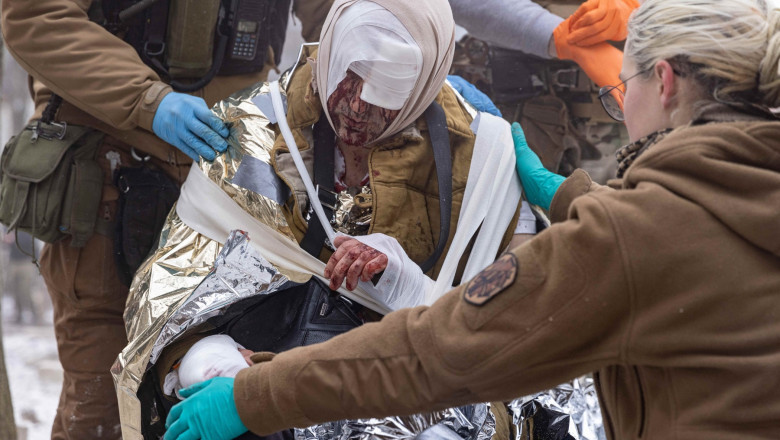 Health service man puts an aluminum blanket on an injured man after Russian rocket strikes on a residential building in kharkiv