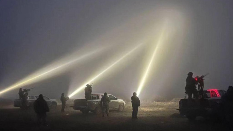 soldati ucraineni cu arme si lampi puternice urmaresc cerul noaptea