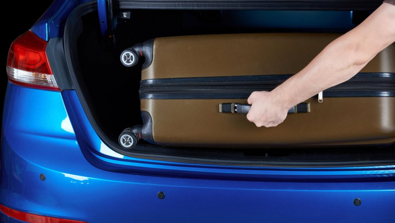 Man take luggage bag from modern car trunk close-up. Hand putting suitcase in blue modern car