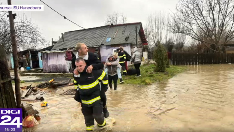 Tineri cărați în spate de pompieri, în apă până la glezne.