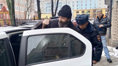 bărbat cu căciulă băgat într-o mașină de un polițist
