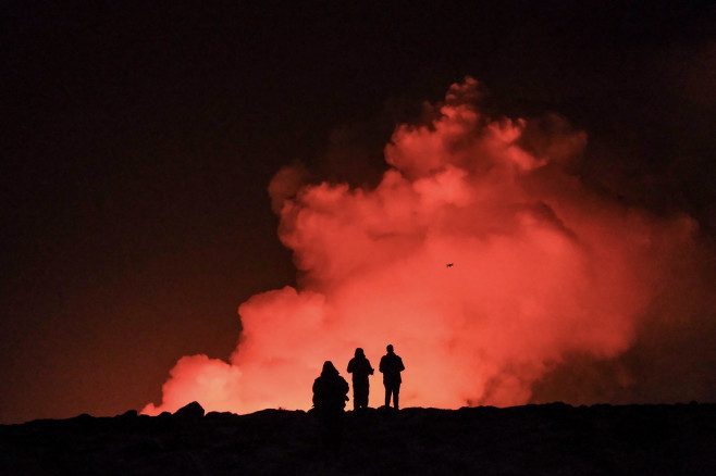 oameni care privesc o eruptie vulcanica in islanda