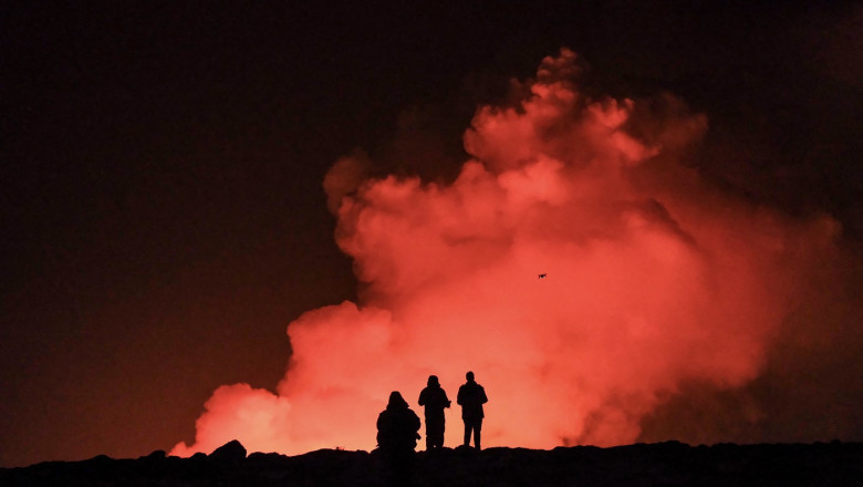 oameni care privesc o eruptie vulcanica in islanda