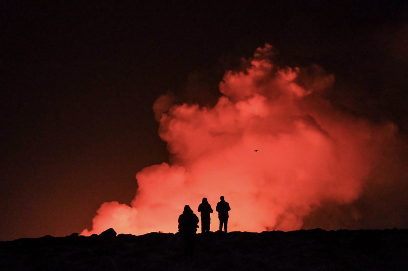 oameni care privesc o eruptie vulcanica in islanda