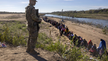 Un militar din Garda Națională a Texasului supraveghează peste 1.000 de migranți care au traversat ilegal fluviul Rio Grande din Mexic în SUA.