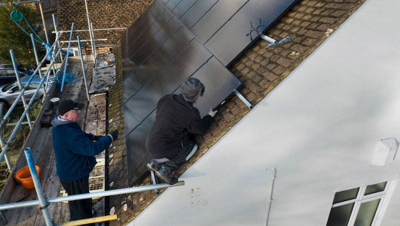 oameni care monteaza panouri fotovoltaice pe casa