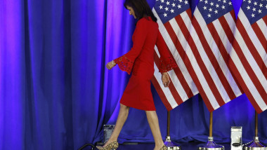 Nikki Haley în rochie roșie cu steaguri americane în spate pleacă de pe o scenă