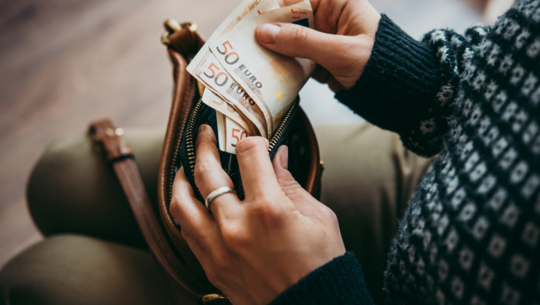 femeie cu un portofel in mana in timp ce numara banii