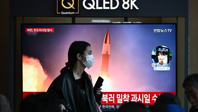o femeie trece in fata unui ecran unde se vede i imagine o racheta lansata de coreea de nord