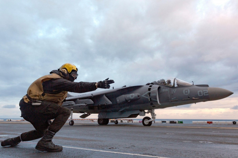 Norfolk, United States. 06th Dec, 2022. A U.S. Navy yellow vest signals a Marine Corps AV-8B Harrier II fighter aircraft with the Ace of Spades of Marine Attack Squadron 231, for take off from the flight deck of the Wasp-class amphibious assault ship USS