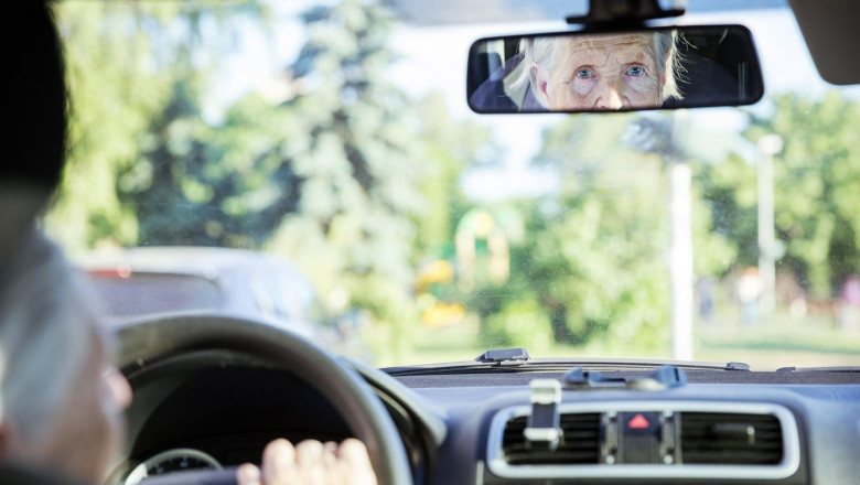 Reflection of senior woman in rear view mirror, aged lady driving car