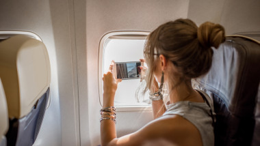 Young,Woman,Photographing,View,From,The,Aircraft,Window,During,The