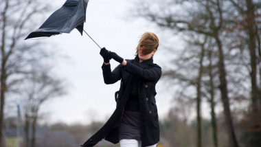 femeie cu o umbrela intoarsa de vant