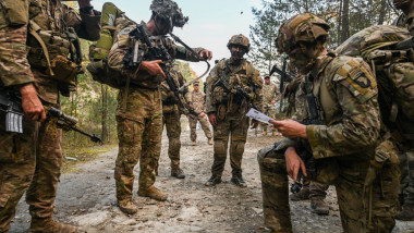 Parașutiști din divizia 101 aeropurtată a SUA stau pe marginea unui drum și consultă o hartă în cadrul unui exercițiu NATO în Polonia