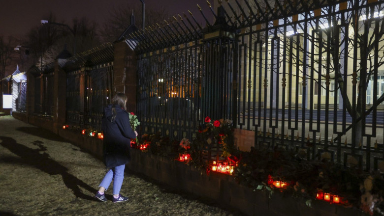 o femeie pune candele si flori in memoria celor ucisi in masacrul de la moscova