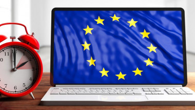 European daylight saving time end. Red alarm clock and eu flag on a laptop screen on wooden desk, banner. 3d illustration