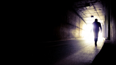 bărbat merge spre lumina de la capătul tunelului