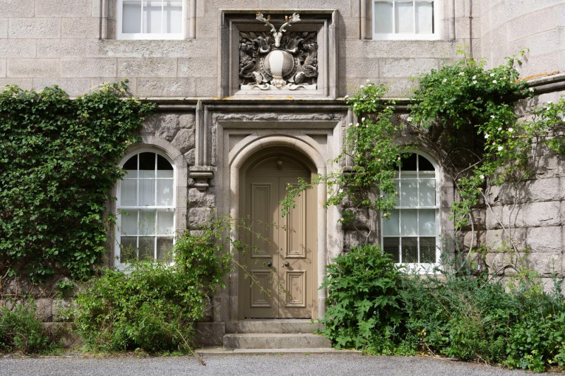 The Entrance Door to Balmoral Castle Tower, Surrounded by Plants and with a Marble Bas Relief Bearing a Crest and Inscription Above the Doorway