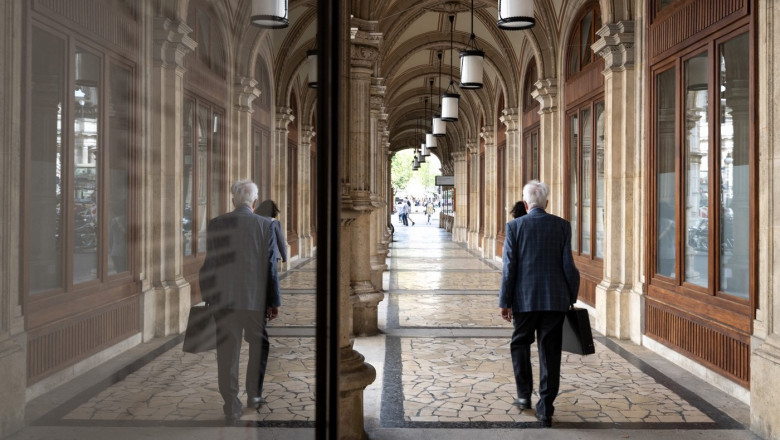 People walk under the stone arches of the Viennese State opera