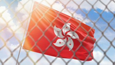 A steel mesh against the background of a blue sky and a flagpole with the flag of hong kong