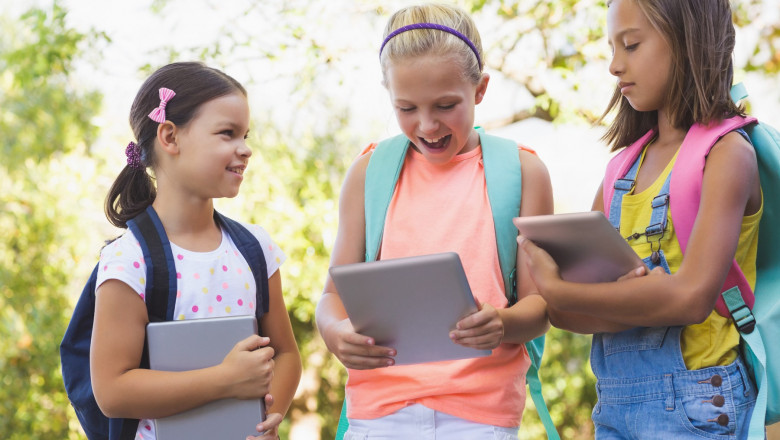 Happy school kids using digital tablet