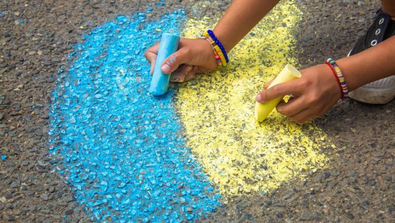 Children draw the Ukrainian flag house on the pavement. Selective focus. child