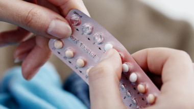 femeie care tine o folie de contraceptive in mana