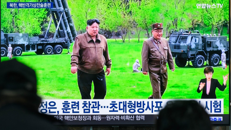 kim jong un si un general pe ecranul u,nui tv, cu lansatoatre de rachete in spate