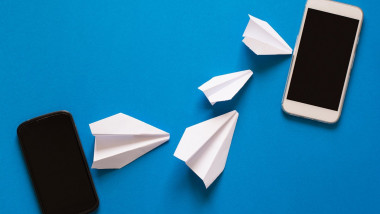Data transfer concept. Message passing. Two mobile smartphones and paper airplanes on blue background. Origami. Paper cut.