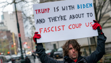 Azzarello ținând în mână pancarte cu mesajul "Trump is with Biden and they're about to fascist coup us""