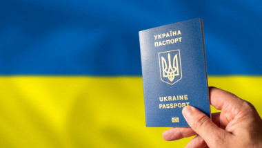 Ukrainian biometric passport in a woman's hand against the background of the national flag of Ukraine. Patriotism, democracy, Independence Day, war in