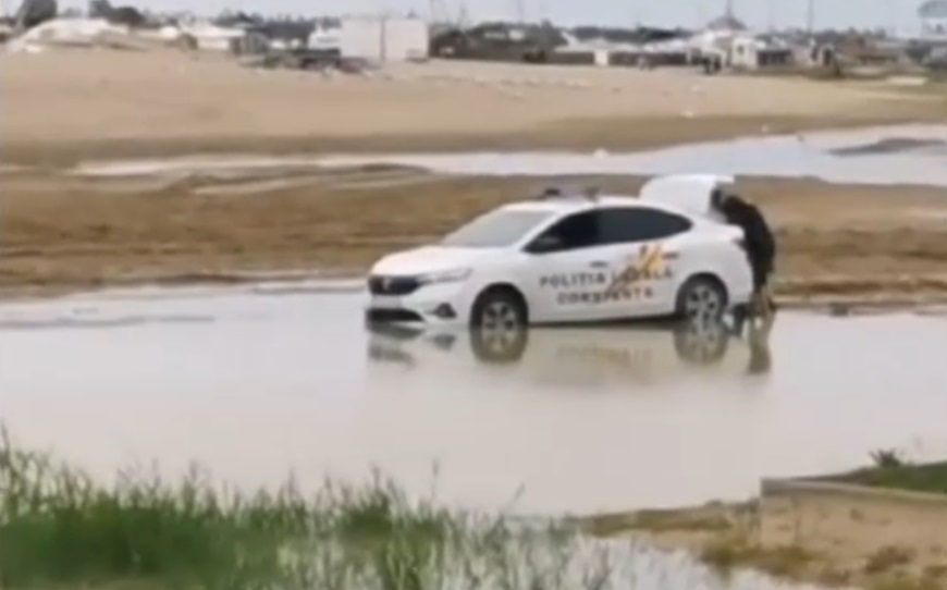 VIDEO Doi polițiști încearcă să-și scoată mașina împotmolită pe plajă. Ce metode au folosit ca să nu-și ude pantofii