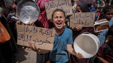 femeie cu recipiente goale și pancarte în Gaza