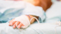 copil cu branula la mana pe patul de spital