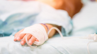 copil cu branula la mana pe patul de spital