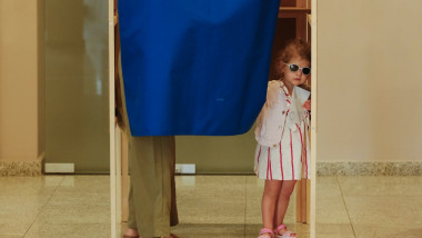 fetita impreuna cu un adult intr-o cabina de vot
