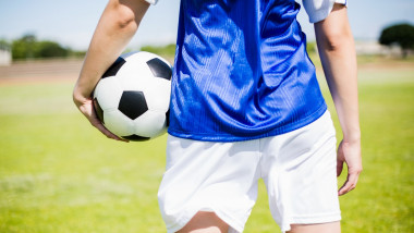 Mid-section of soccer player standing with a ball