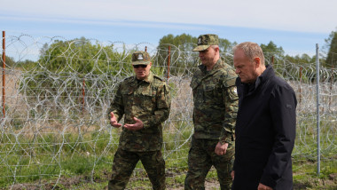 premierul polonez Donald Tusk, încadrat de militari polonezi, inspectează un gard de sârmă ghimpată la granița Poloniei cu Belarus