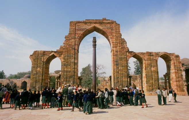 India: The remains of the Quwwat-ul-Islam Mosque and in the foreground the almost 2,000 year old Iron Pillar at the Qutb Minar complex, Delhi