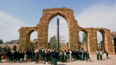 India: The remains of the Quwwat-ul-Islam Mosque and in the foreground the almost 2,000 year old Iron Pillar at the Qutb Minar complex, Delhi