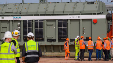 Technicians and engineers stand in front of a transformer at the Wolmirstedt substation and confer in germany