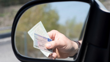 mana de barbat cu documentele masina si permisul de conducere